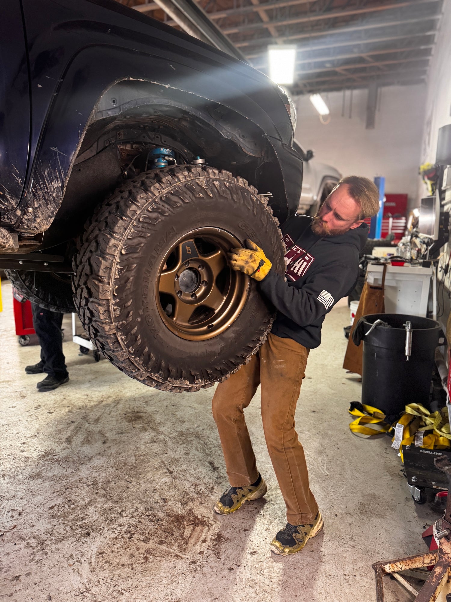 A mechanic at Sexton Offroad Park City working on a 4x4 vehicle in the shop, performing repairs and upgrades with precision and expertise.